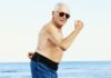 glad ældre mand i badebukser flekser muskler
